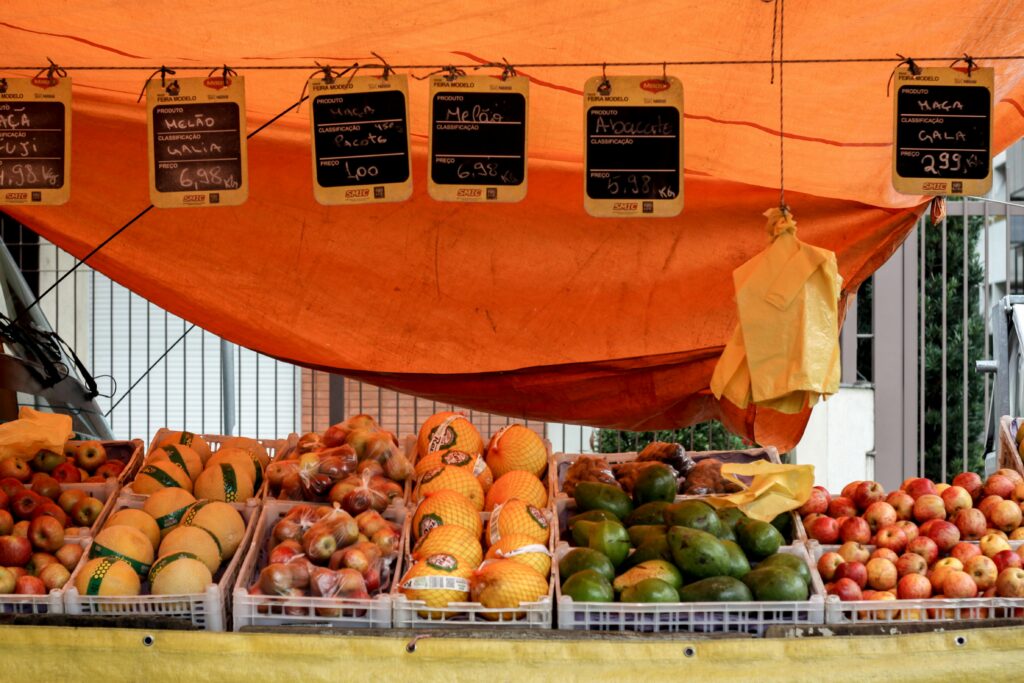 Tasty ripe apples near avocados and melons for sale in cardboard boxes in local bazaar