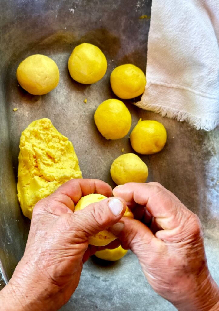 Hands shaping pão de queijo dough, a Brazilian tradition.